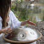 Person playing a handpan by a pond